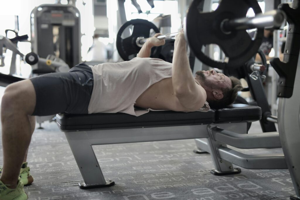 A man performing an intense bench press workout in a modern gym, showcasing strength and focus.